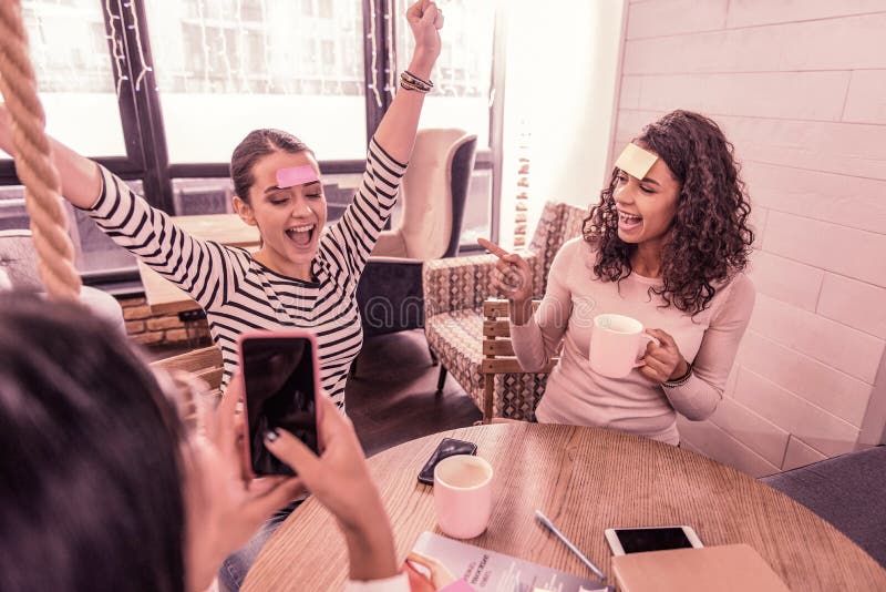 Dark-haired woman wearing striped shirt feeling happy after winning the word game stock photo Dark-haired woman wearing striped shirt feeling happy after winning the word game stock photo