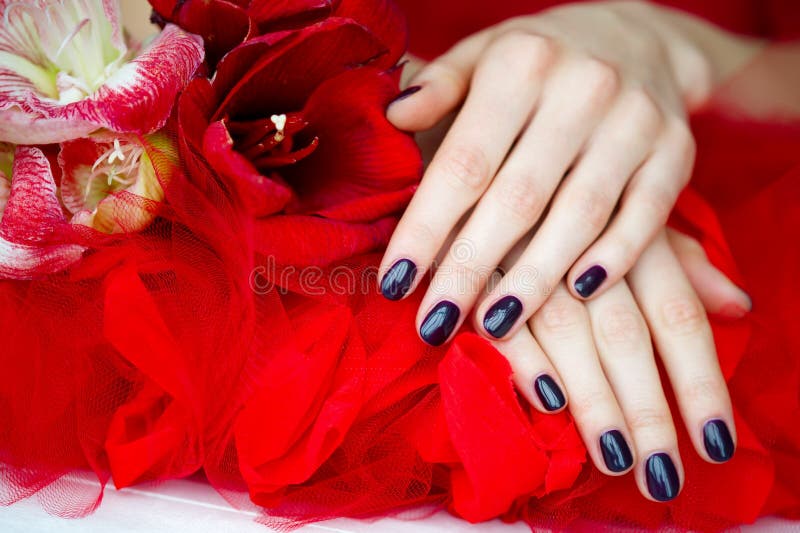 Dark manicure and flowers on red