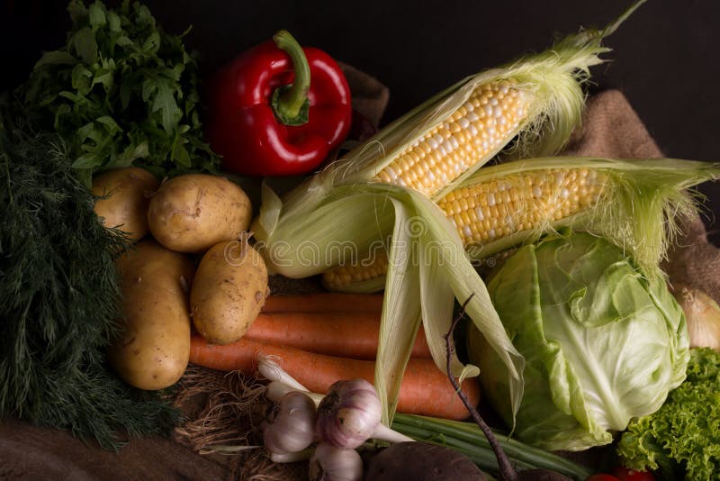 Dark moody still life of fresh vegetables on a wooden table. Healthy organic local food