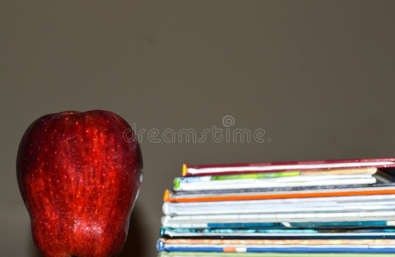 A dark photo of an apple beside a stack of children`s book for education stock image A dark photo of an apple beside a stack of children`s book for education stock image