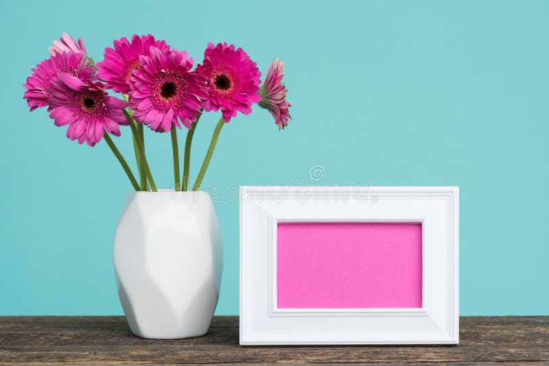 Dark pink gerberas in a vase on a table with empty picture frame greeting card. stock image Dark pink gerberas in a vase on a table with empty picture frame greeting card. stock image