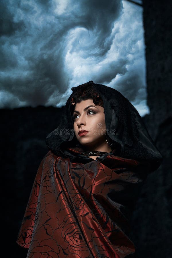 Dark queen of the ghost in a dark castle collapsed, visible destruction of the castle wall and dark storm clouds