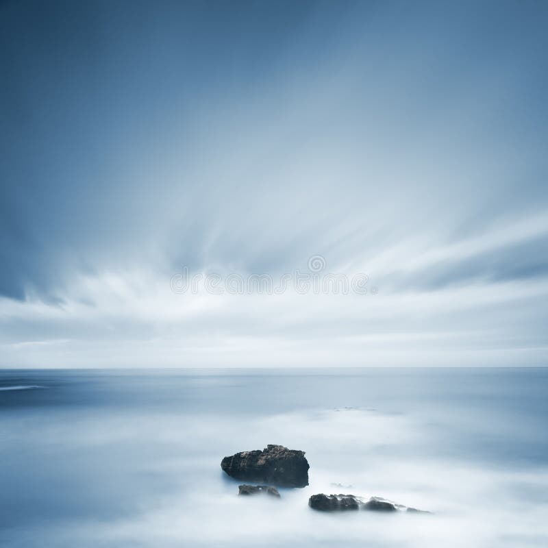 Dark rocks in a blue ocean under cloudy sky in a bad weather. stock photo Dark rocks in a blue ocean under cloudy sky in a bad weather. stock photo