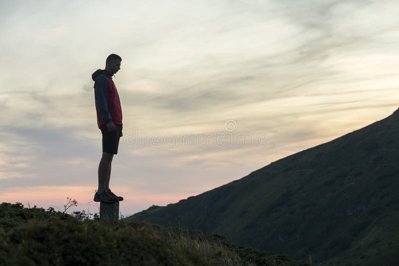 Dark silhouette of a hiker on a mountain at sunset standing on summit like a winner royalty free stock image Dark silhouette of a hiker on a mountain at sunset standing on summit like a winner royalty free stock image