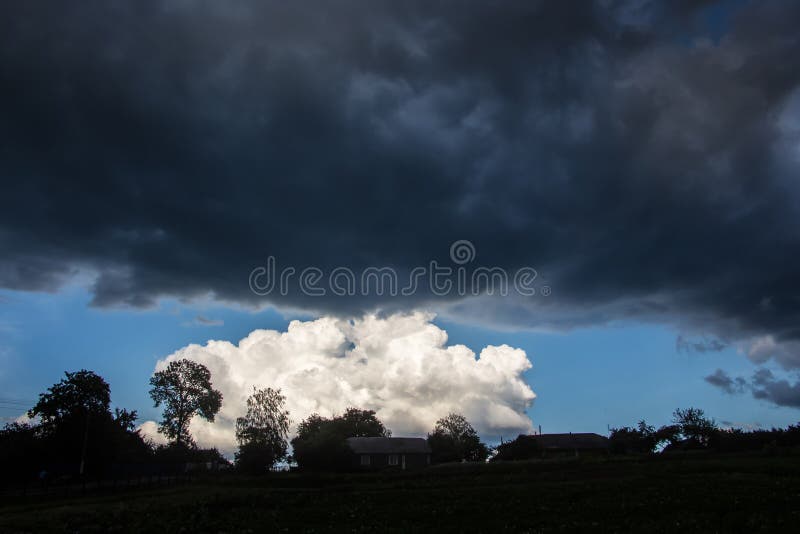 Dark storm clouds over a small white cloud. Different clouds during a thunderstorm. Dark and bright clouds in the sky. The