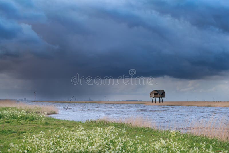 Dark stormy sky over Dollard coast with tower, Netherlands