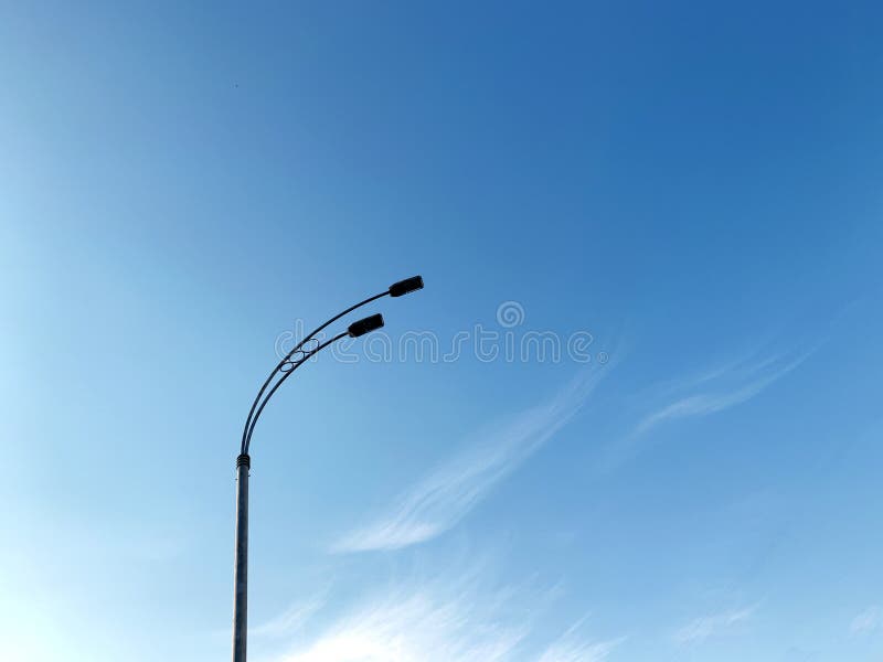 Dark street lamp silhouette on blu sky background with clouds