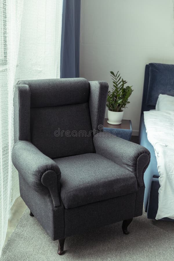 Dark Upholstered Armchair in Traditional Light Bedroom Stock Image