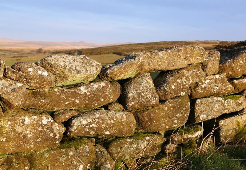 Detail of ancient weathered dry stone wall, covered in lichen and mosses, Dartmoor, Devon. Lit by early morning sunlight. Detail of ancient weathered dry stone wall, covered in lichen and mosses, Dartmoor, Devon. Lit by early morning sunlight.