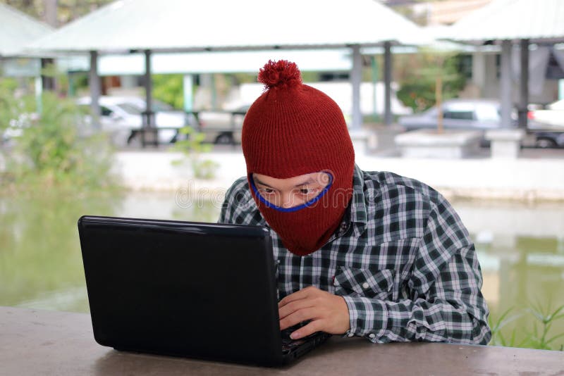 Das anonyme Hackerzerhacken stehlen Daten mit Laptop lizenzfreies stockbild