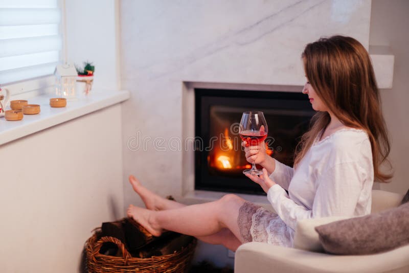 Das attraktive Mädchen, das durch den Schornstein mit einem Glas Wein beruht lizenzfreie stockfotografie