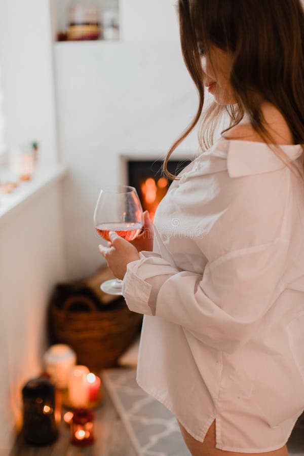 Das hübsche Mädchen, das sich am Kamin mit einem Glas Wein entspannt stockfotos