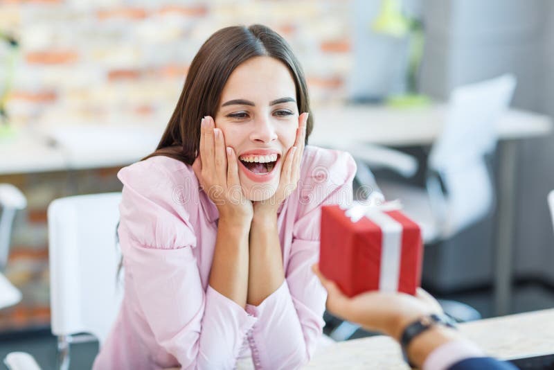 Das glückliche Mädchen, das im Büro arbeitet, empfing ein Geschenk lizenzfreies stockbild Das glückliche Mädchen, das im Büro arbeitet, empfing ein Geschenk lizenzfreies stockbild