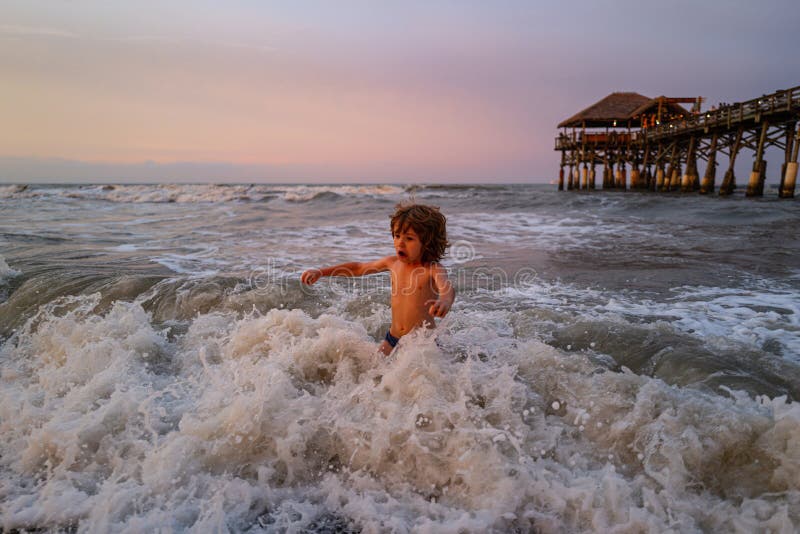 Das Kind neben den Wellen springend. Frohe Kind haben Spaß im Meer am Strand. Tätigkeits-Sommerlager des Reiselebensstils Überstan lizenzfreie stockfotos