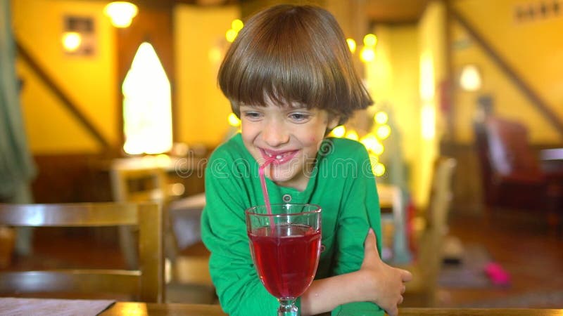 Das Kind trinkt Saft Porträt Beeren-Saft Smoothie des glücklichen kleinen netten Jungen trinkenden durch Stroh und das Lächeln