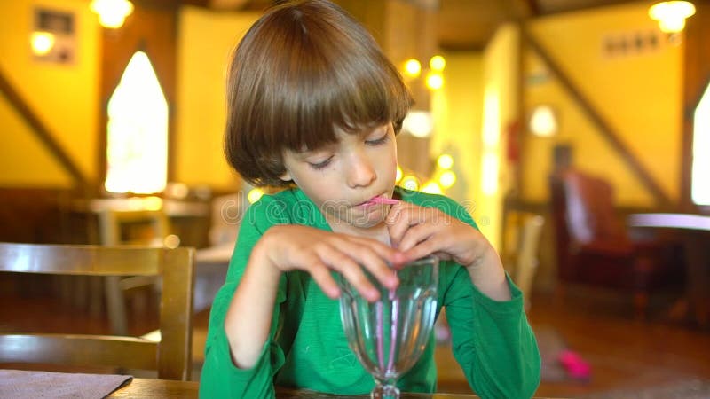 Das Kind trinkt Saft Porträt Beeren-Saft Smoothie des glücklichen kleinen netten Jungen trinkenden durch Stroh und das Lächeln