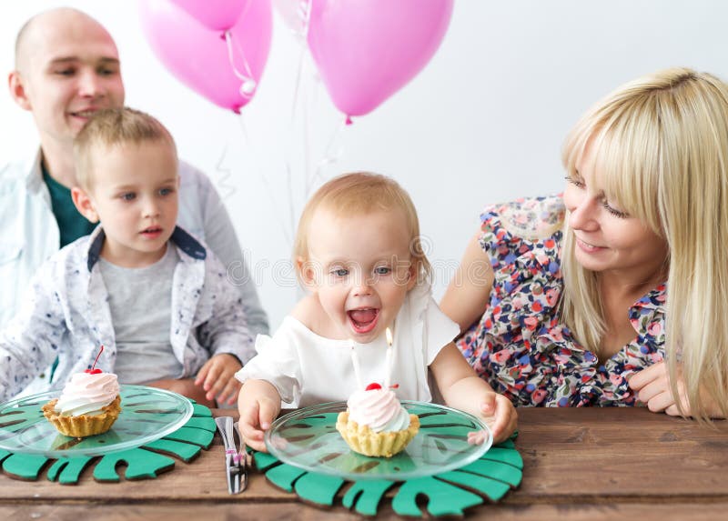 Das kleine Mädchen brennt heraus die Kerze durch Glückliche Familie, die einen Geburtstagsfeiergeburtstag der Tochter feiert lizenzfreies stockfoto Das kleine Mädchen brennt heraus die Kerze durch Glückliche Familie, die einen Geburtstagsfeiergeburtstag der Tochter feiert lizenzfreies stockfoto