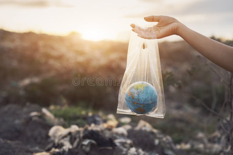 The concept of world environment day. The woman hand holds the earth in a plastic bag on garbage pile in trash dump or landfill backgound. Pollution concept. The concept of world environment day. The woman hand holds the earth in a plastic bag on garbage pile in trash dump or landfill backgound. Pollution concept