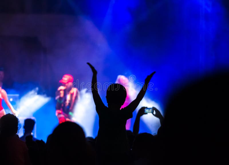 Das Konzertpublikum, das an einem Konzert teilnimmt, Leuten, die Schattenbilder sichtbar sind, hintergrundbeleuchtet durch Stadiu lizenzfreies stockfoto Das Konzertpublikum, das an einem Konzert teilnimmt, Leuten, die Schattenbilder sichtbar sind, hintergrundbeleuchtet durch Stadiu lizenzfreies stockfoto