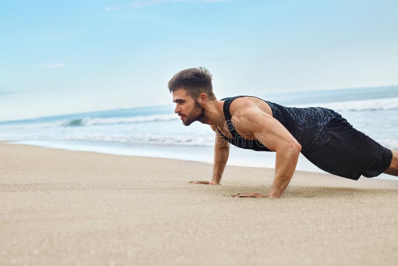 Das Mann-Trainieren, tuend drücken Übungen auf Strand hoch Eignungstraining stockbild Das Mann-Trainieren, tuend drücken Übungen auf Strand hoch Eignungstraining stockbild