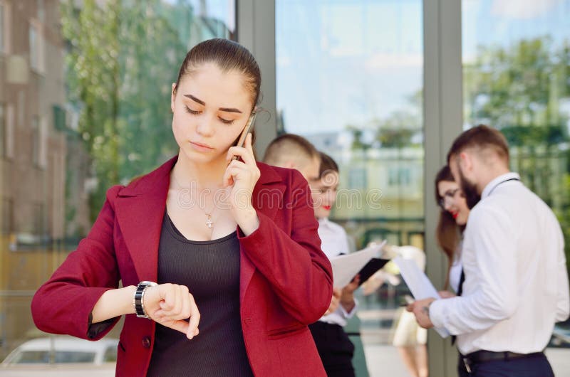 Das Mädchen betrachtet die Armbanduhr Junges Team der Büroarbeit lizenzfreie stockfotos Das Mädchen betrachtet die Armbanduhr Junges Team der Büroarbeit lizenzfreie stockfotos