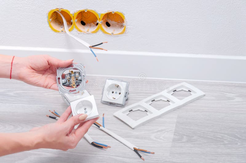 Das Mädchen steckt das Kabel an eine Steckdose Reparatur im Haus Ersetzen einer alten Steckdose lizenzfreies stockbild Das Mädchen steckt das Kabel an eine Steckdose Reparatur im Haus Ersetzen einer alten Steckdose lizenzfreies stockbild