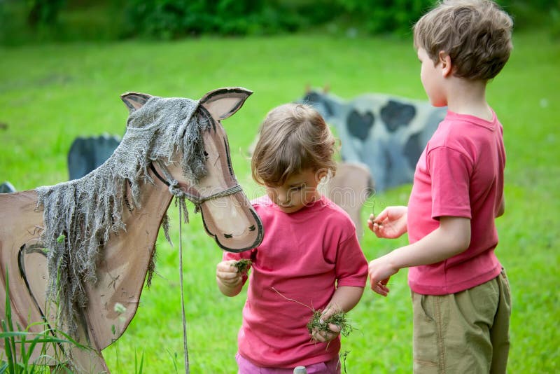 Das Mädchen und der Junge speisen ein hölzernes Pferd stockbild Das Mädchen und der Junge speisen ein hölzernes Pferd stockbild