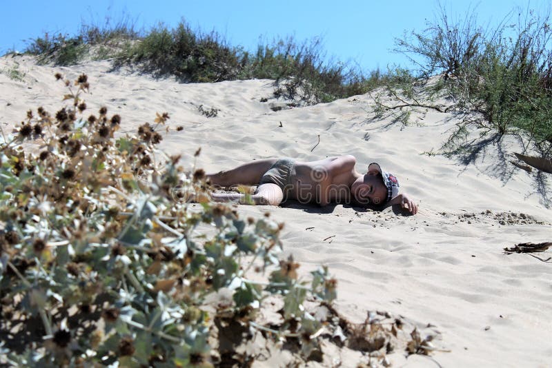 Das müde Lügen des schönen Babys auf dem Sand und bräunen sich und Stillstehen stockbild Das müde Lügen des schönen Babys auf dem Sand und bräunen sich und Stillstehen stockbild