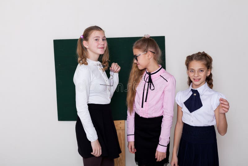 Das Schulmädchen mit drei Mädchen steht an der Tafel mit Lektion stockfoto