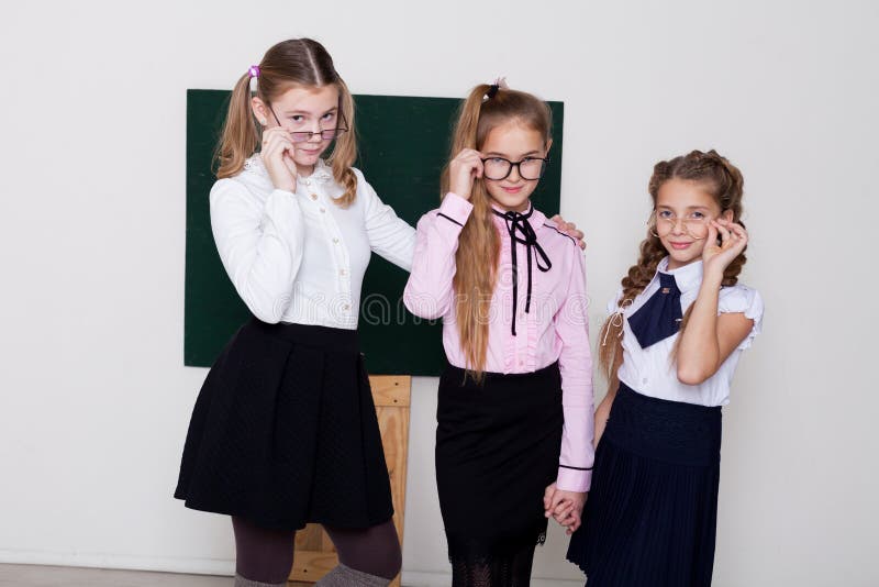 Das Schulmädchen mit drei Mädchen steht an der Tafel mit Lektion lizenzfreie stockfotografie