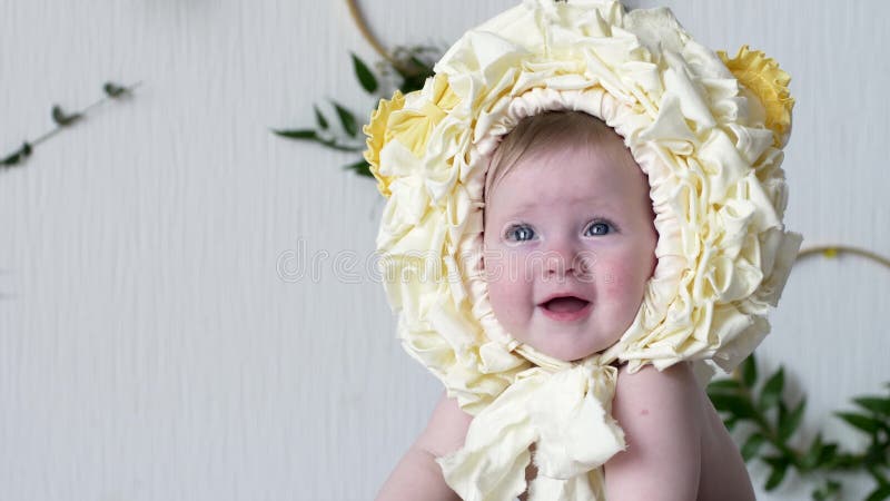 Das schöne Kleinkind, das gelben Kopfschmuck trägt, wirft an der Kamera auf photoshoot auf