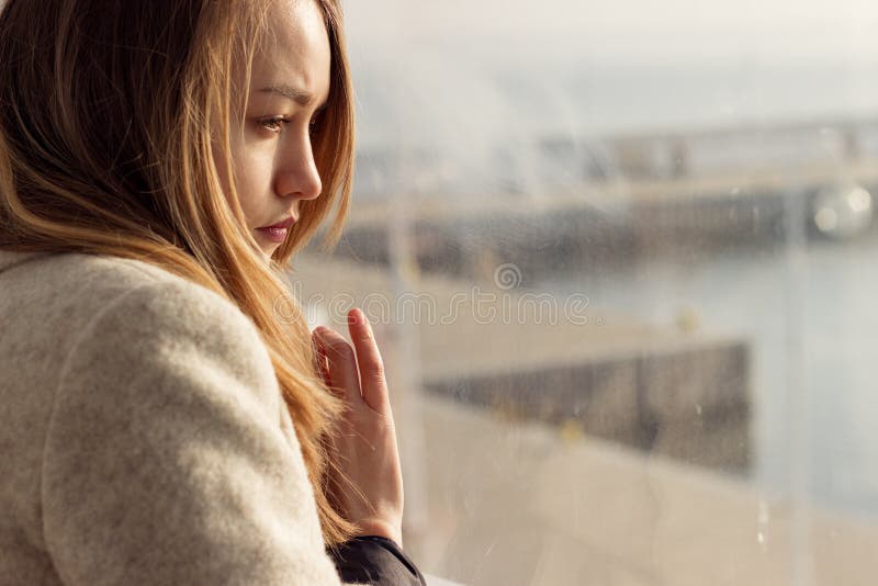 Das schöne traurige einsame Mädchen, das nahe dem Fenster sitzt, fehlt lizenzfreie stockfotos