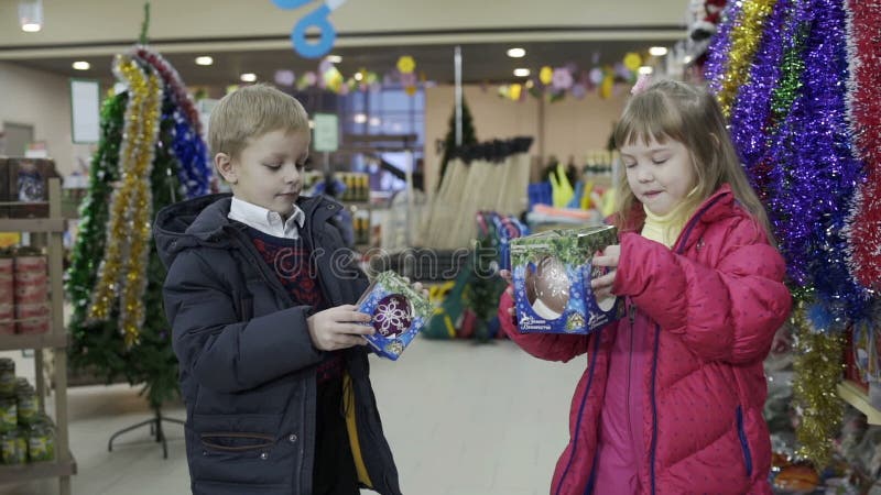 Das wenig nette Mädchen- und Jungenwählen verzieren für Weihnachten-Baum im Einkaufszentrum