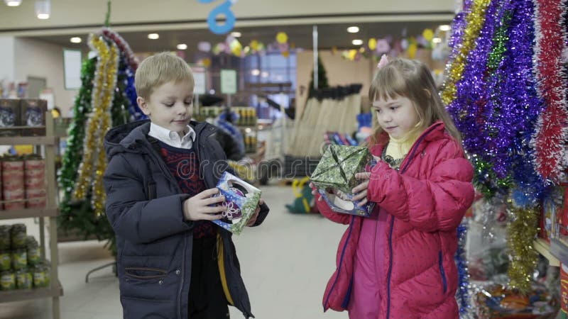 Das wenig nette Mädchen- und Jungenwählen verzieren für Weihnachten-Baum im Einkaufszentrum