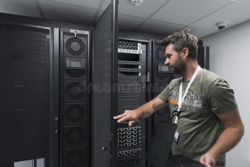Data Center Engineer Usaing Keyboard on a Supercomputer Server Room Specialist Facility with Male System Administrator royalty free stock image