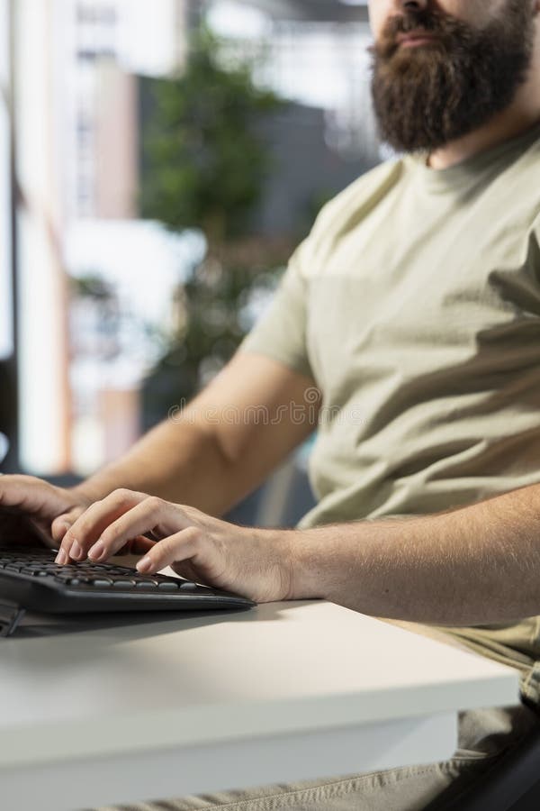 Close up of man in office typing on keyboard, doing software quality assurance royalty free stock photo