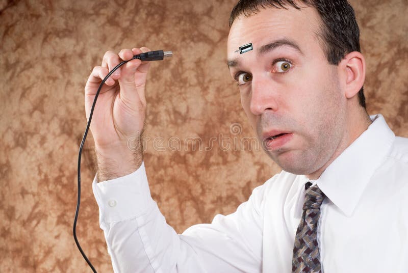 A man about to plug a USB cable into his forhead to transfer data. Usb data transfer stock images, royalty-free photos and pictures