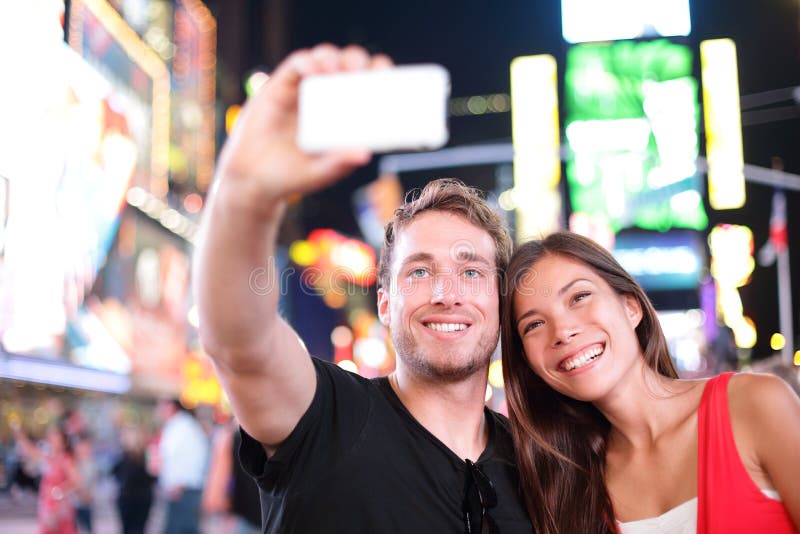 Datando os pares novos felizes no amor que toma a foto do selfie no Times Square, New York City na noite. Turista multirracial nov fotos de stock royalty free Datando os pares novos felizes no amor que toma a foto do selfie no Times Square, New York City na noite. Turista multirracial nov fotos de stock royalty free