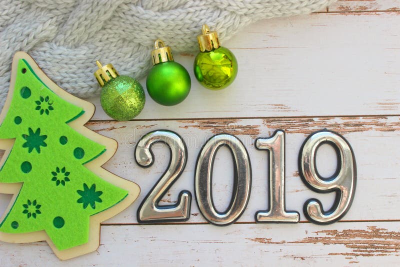 Date is 2019, three-dimensional figures. New year background. Christmas decorations. Christmas background. Christmas toys, green balls on a background of white wood. Copy space.