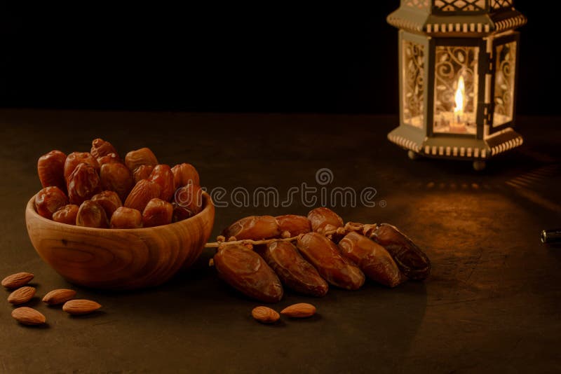 Dates in wooden bowl and lantern on stone table. Muslim holy month Ramadan Kareem. Copy space stock photos Dates in wooden bowl and lantern on stone table. Muslim holy month Ramadan Kareem. Copy space stock photos
