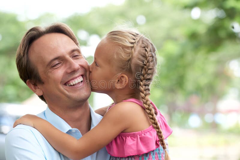 Little girl kissing her laughing father on cheek royalty free stock images.