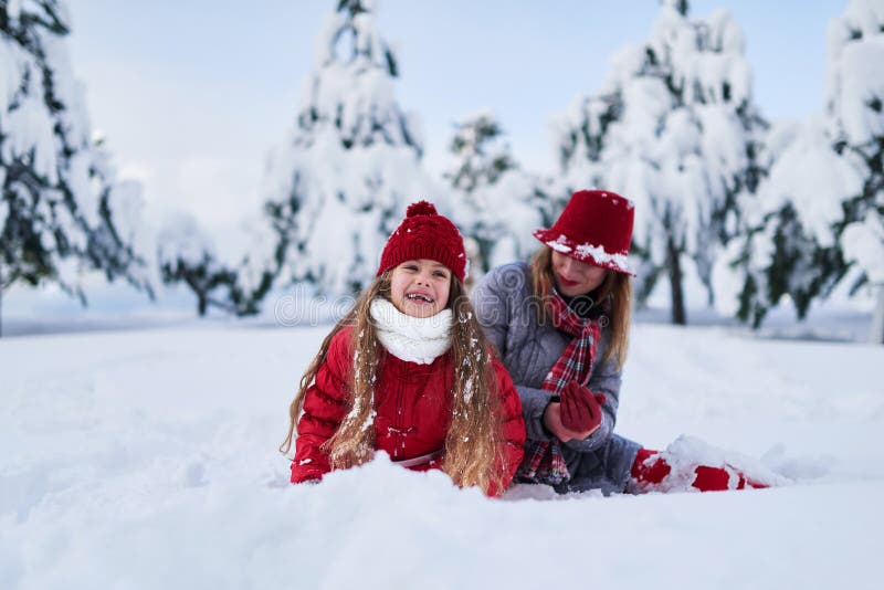 Daughter with mother play in snow-covered park