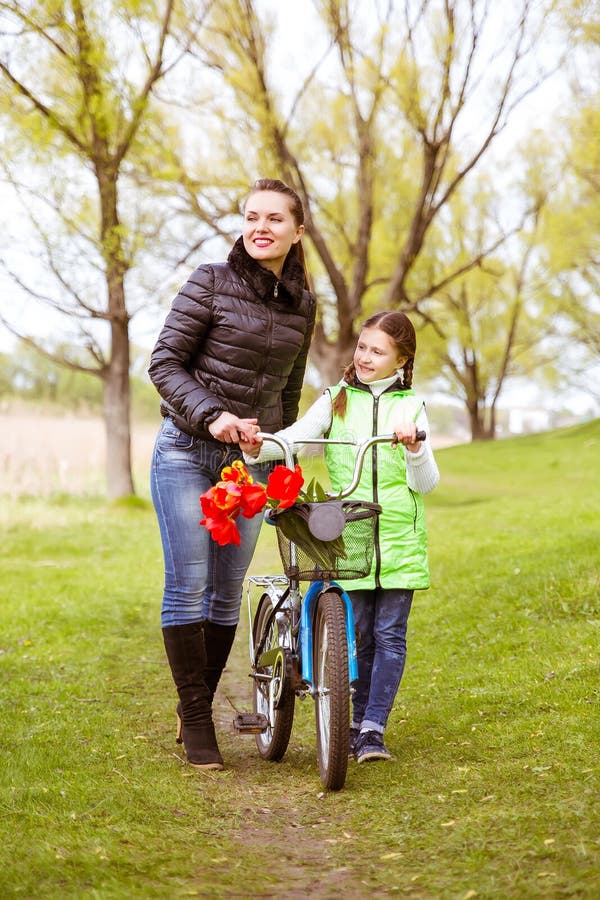 Daughter and mother walk along the shore of the lake with a bike and talk. Family values, education stock image Daughter and mother walk along the shore of the lake with a bike and talk. Family values, education stock image