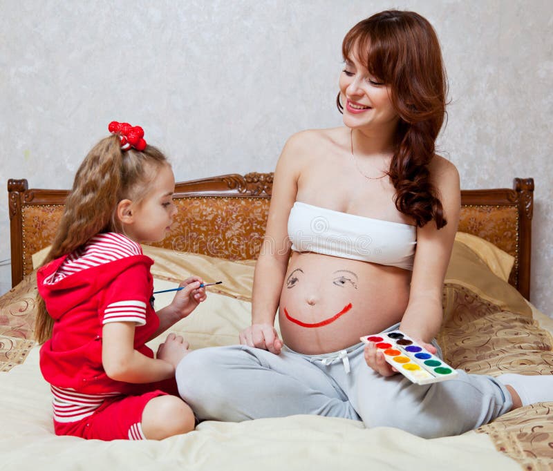 A daughter is painting on her mother`s belly