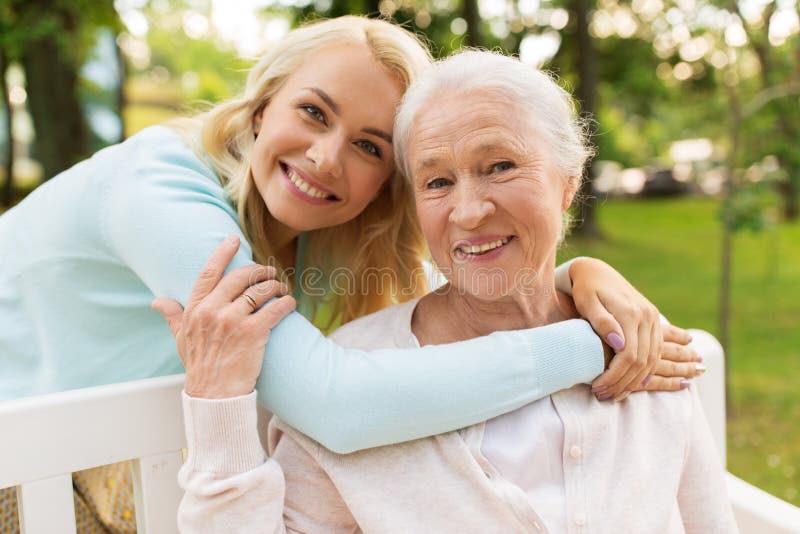 Daughter with senior mother hugging on park bench