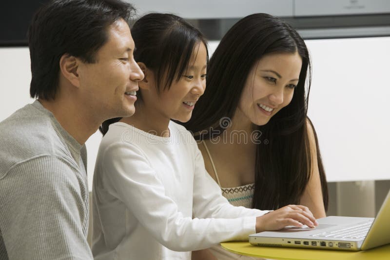 Daughter Using Laptop with Mother and Father in Living Room Stock Photo