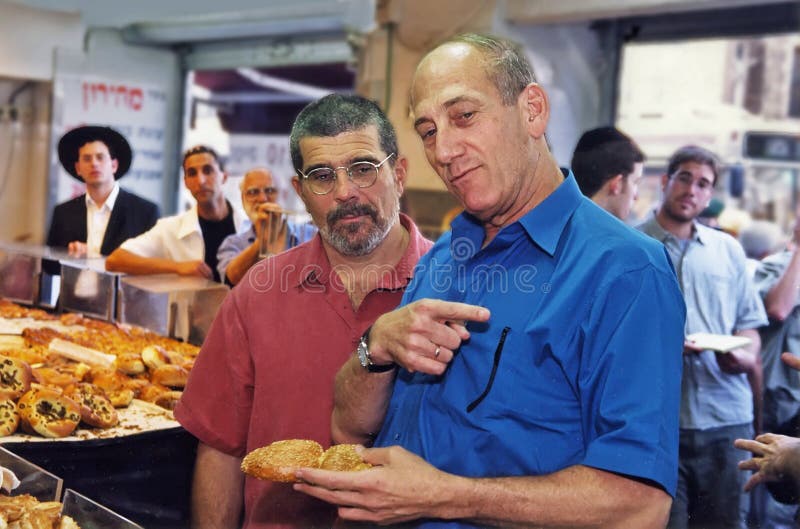 Then Jerusalem, Israel, mayor Ehud Olmert, plays tour guide to American playwright David Mamet in July, 1993. Here he describes the finer points of a bread shop at the capital's busy Machne Yehuda market. Olmert was mayor of Jerusalem from 1993-2003 while a member of the Likud Party, and was prime minister from 2006-2009, while leading the Kadima Party. He was a Member of the Knesset (parliament) and a former Minister of Health. Olmert was Deputy Prime Minister under Ariel Sharon and during Sharonâ€™s illness became acting-Prime Minister. When Sharon did not come out of his coma from a stroke, he took over as PM. He was a pragmatic leader when it came to negotiations with the Palestinians. But under his helm the nation became embroiled in armed conflicts with Lebanon and Gaza. His administration was also plagued with allegations of corruption and he relinquished leadership of his party in 2009. On March 31, 2014 he was convicted of bribery charges. Then Jerusalem, Israel, mayor Ehud Olmert, plays tour guide to American playwright David Mamet in July, 1993. Here he describes the finer points of a bread shop at the capital's busy Machne Yehuda market. Olmert was mayor of Jerusalem from 1993-2003 while a member of the Likud Party, and was prime minister from 2006-2009, while leading the Kadima Party. He was a Member of the Knesset (parliament) and a former Minister of Health. Olmert was Deputy Prime Minister under Ariel Sharon and during Sharonâ€™s illness became acting-Prime Minister. When Sharon did not come out of his coma from a stroke, he took over as PM. He was a pragmatic leader when it came to negotiations with the Palestinians. But under his helm the nation became embroiled in armed conflicts with Lebanon and Gaza. His administration was also plagued with allegations of corruption and he relinquished leadership of his party in 2009. On March 31, 2014 he was convicted of bribery charges.