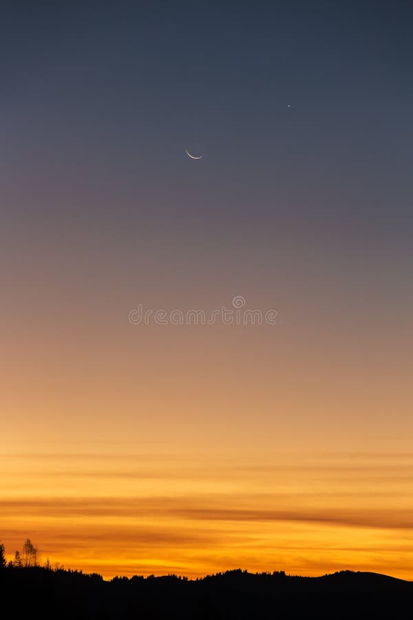 Dawn sky with a moon and stars.
