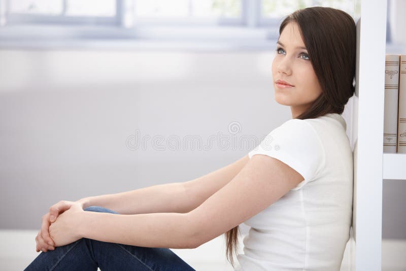 Daydreaming young woman sitting on floor