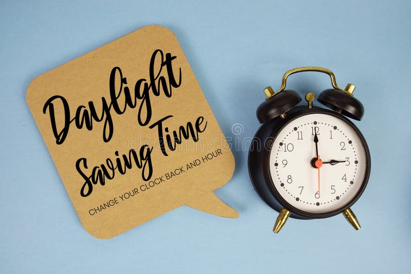 Daylight Saving Time text with alarm clock on blue background stock photo